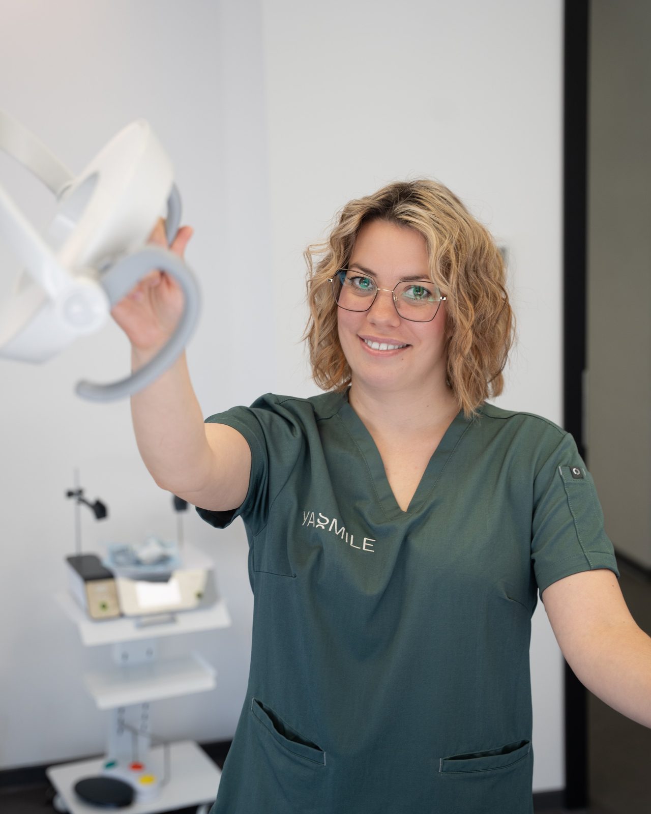 Mitarbeiterin richtet die Behandlungsleuchte im Behandlungszimmer aus